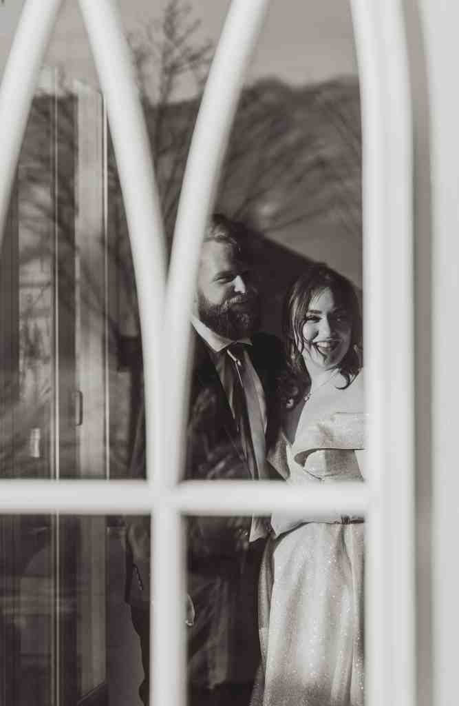 A black and white candid photo of a bride and groom laughing with a guest at their wedding in Kelowna, BC at Sanctuary Gardens