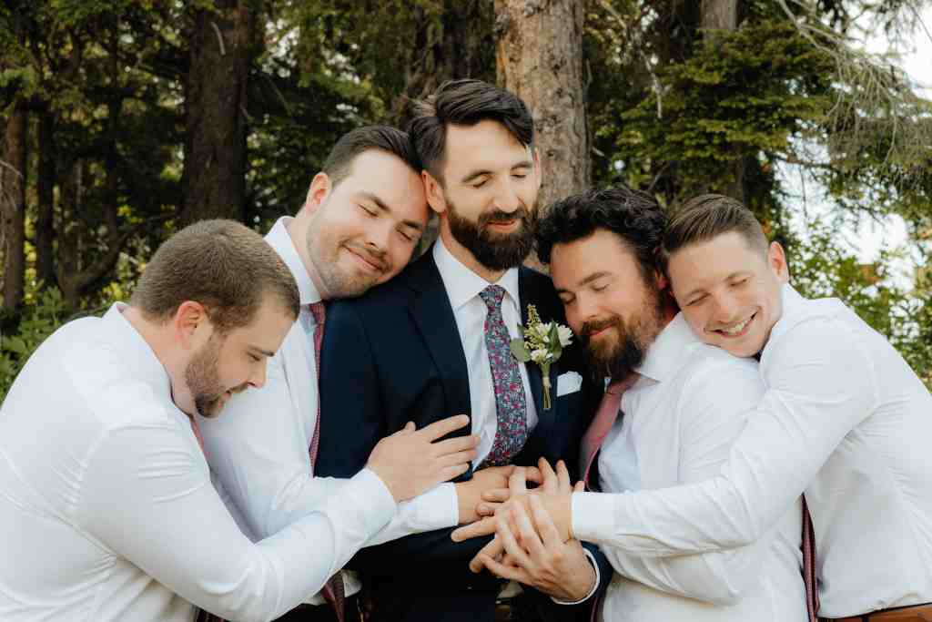 A groom and his groomsmen share a cute hug at a wedding in Revelstoke, BC