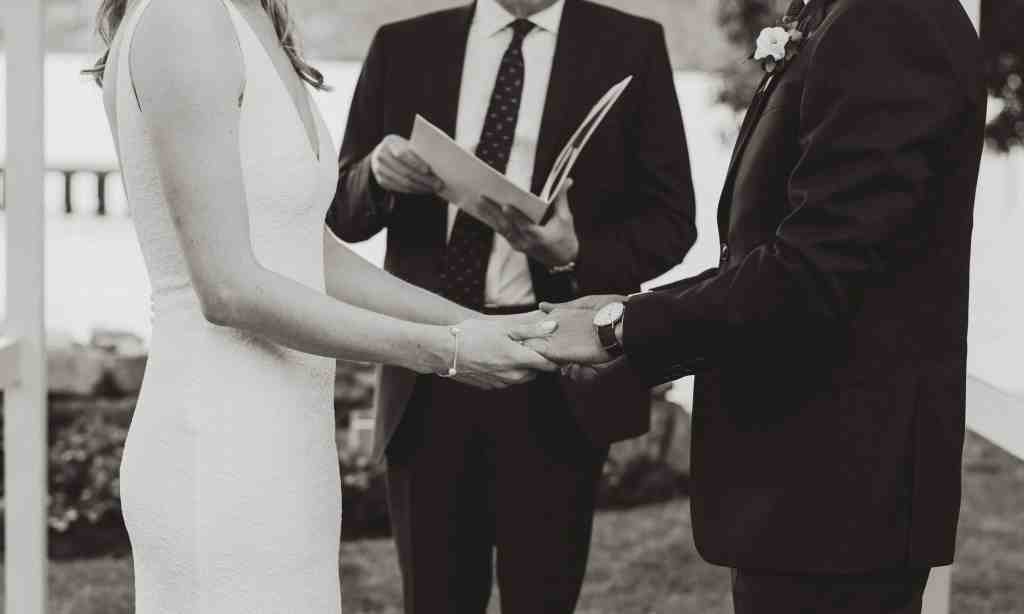 A bride and groom join hands in a beautiful black and white photo at their backyard wedding in Kelowna, British Columbia