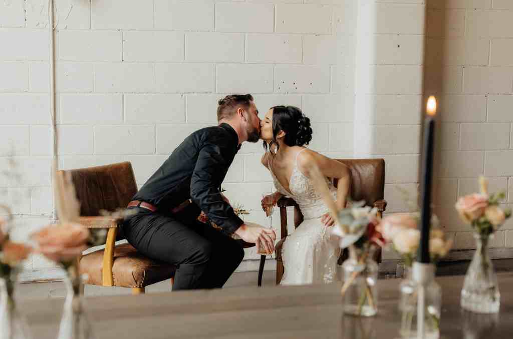 A bride and groom share a kiss in a candid moment behind the scenes at their wedding in Kelowna, BC