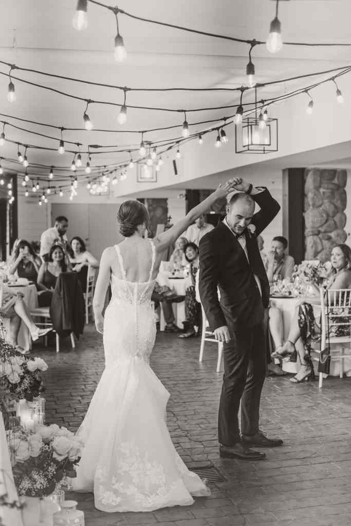 A beautiful black and white shot of a bride and groom's first dance at their wedding reception to their fave wedding songs at Summerhill Winery in the Okanagan