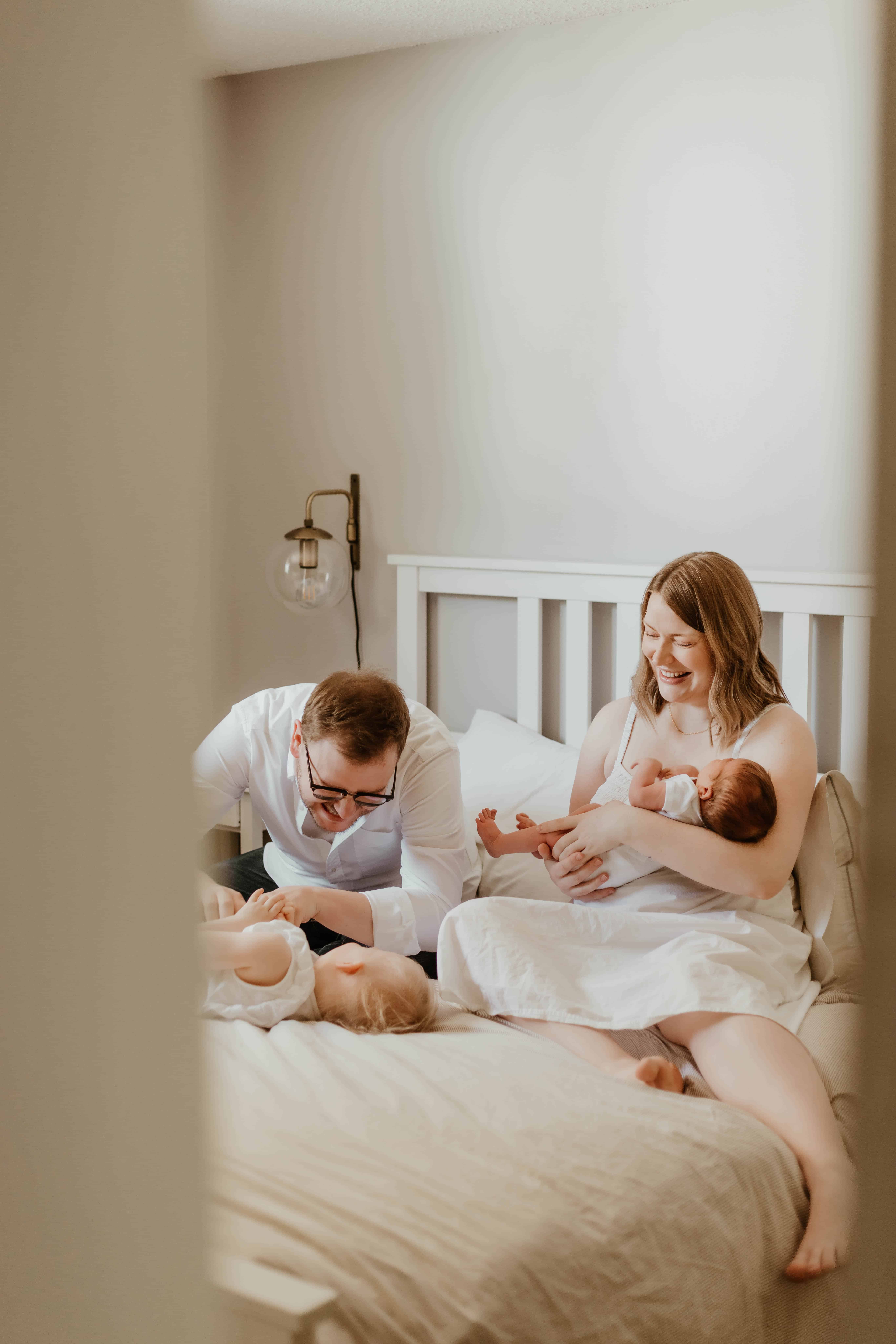 A beautiful candid photo peeking through a door at a family playing together at a cozy home photoshoot in Calgary, AB