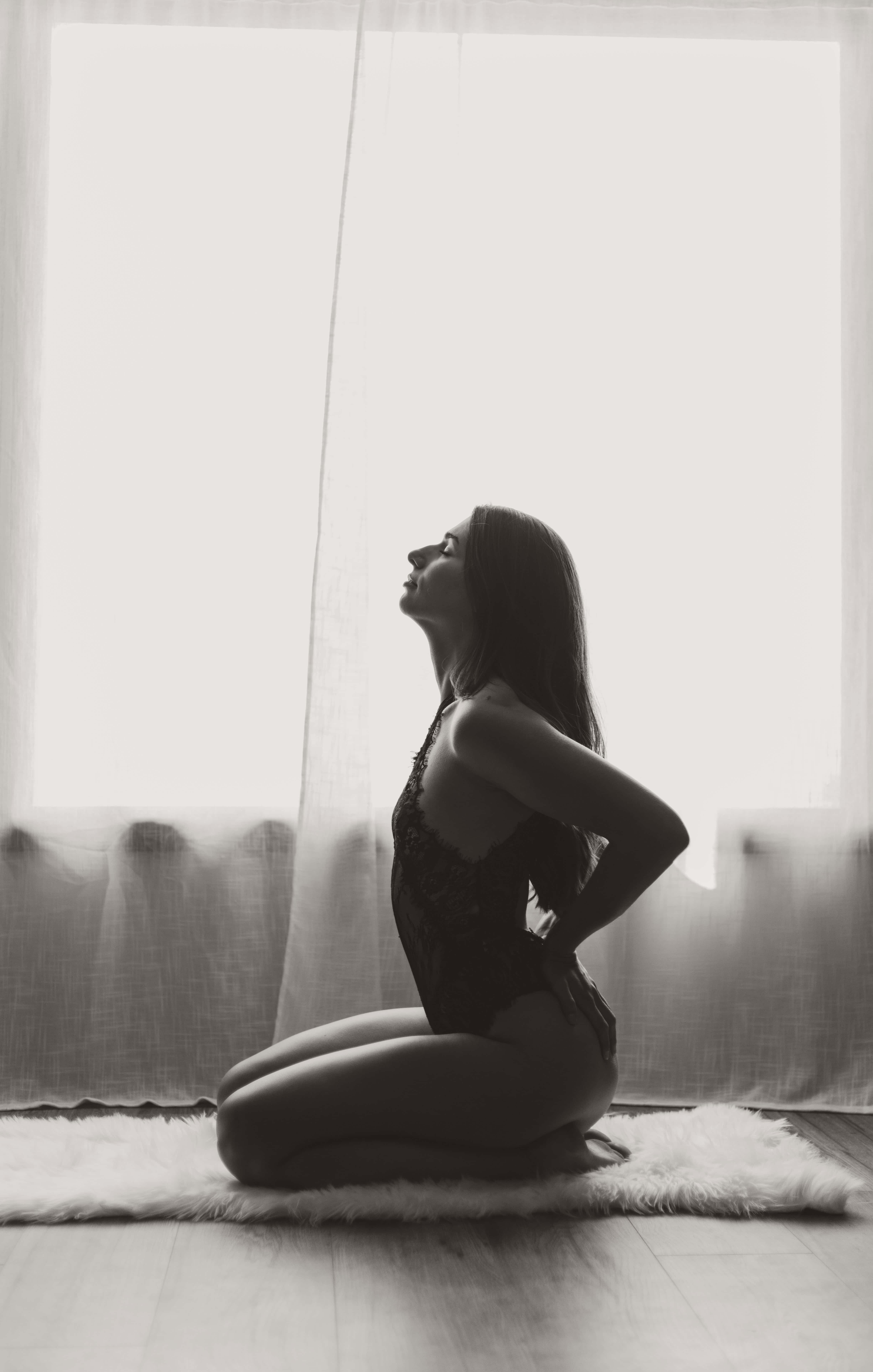 A moody portrait of a confident woman posing for a boudoir session in Kelowna, BC