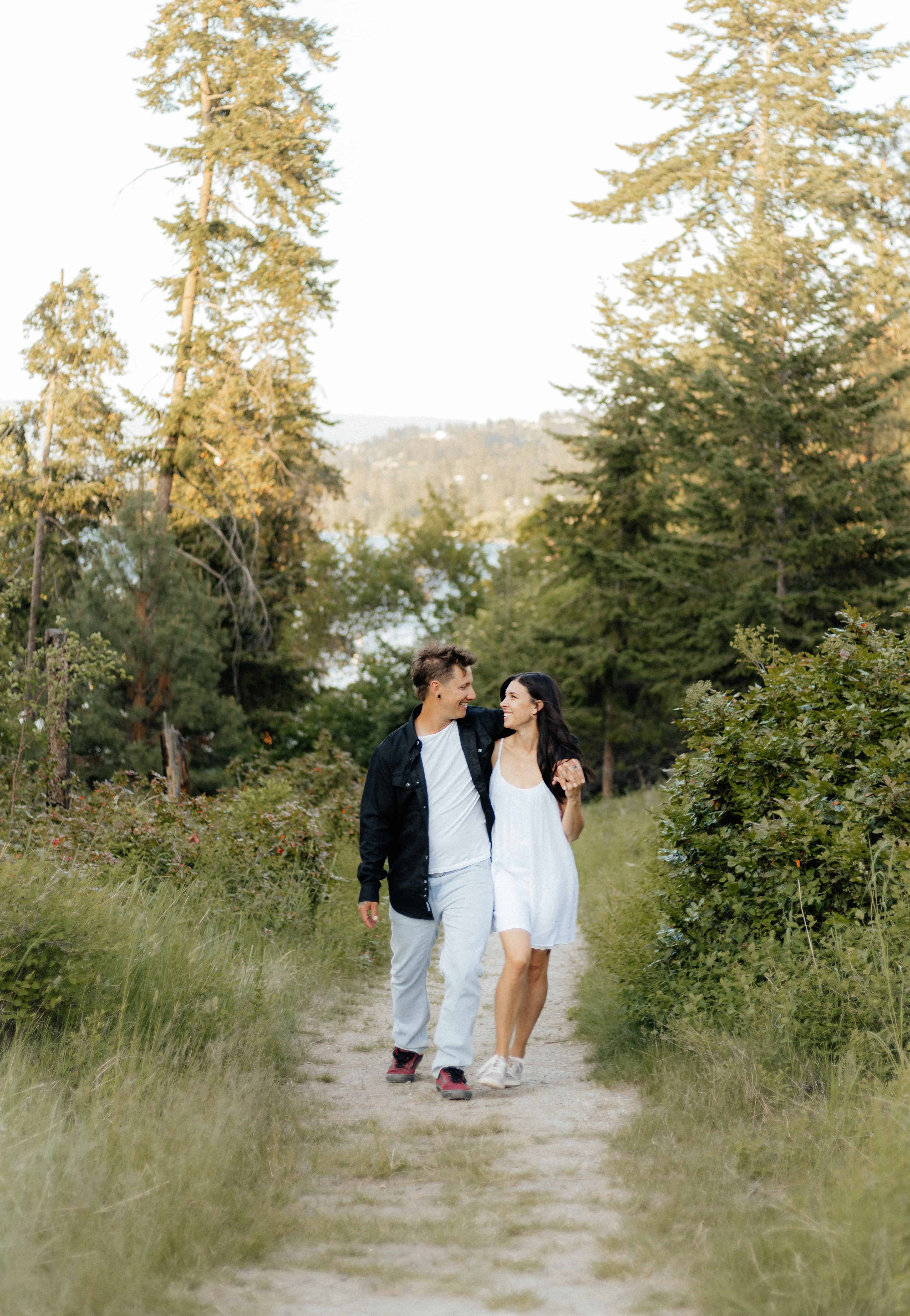A couple casually walks down a winding path while gazing lovingly at each other at Bertram Creek Park, Okanagan