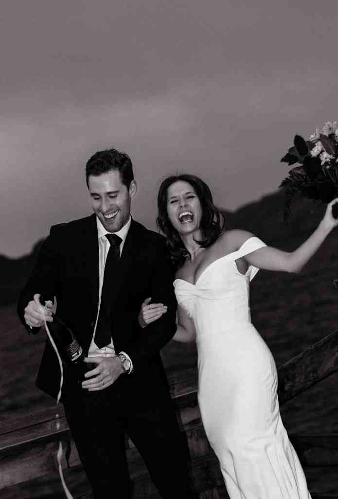 A fun black and white flash shot of a couple during a wedding photography shoot, celebrating and popping champagne