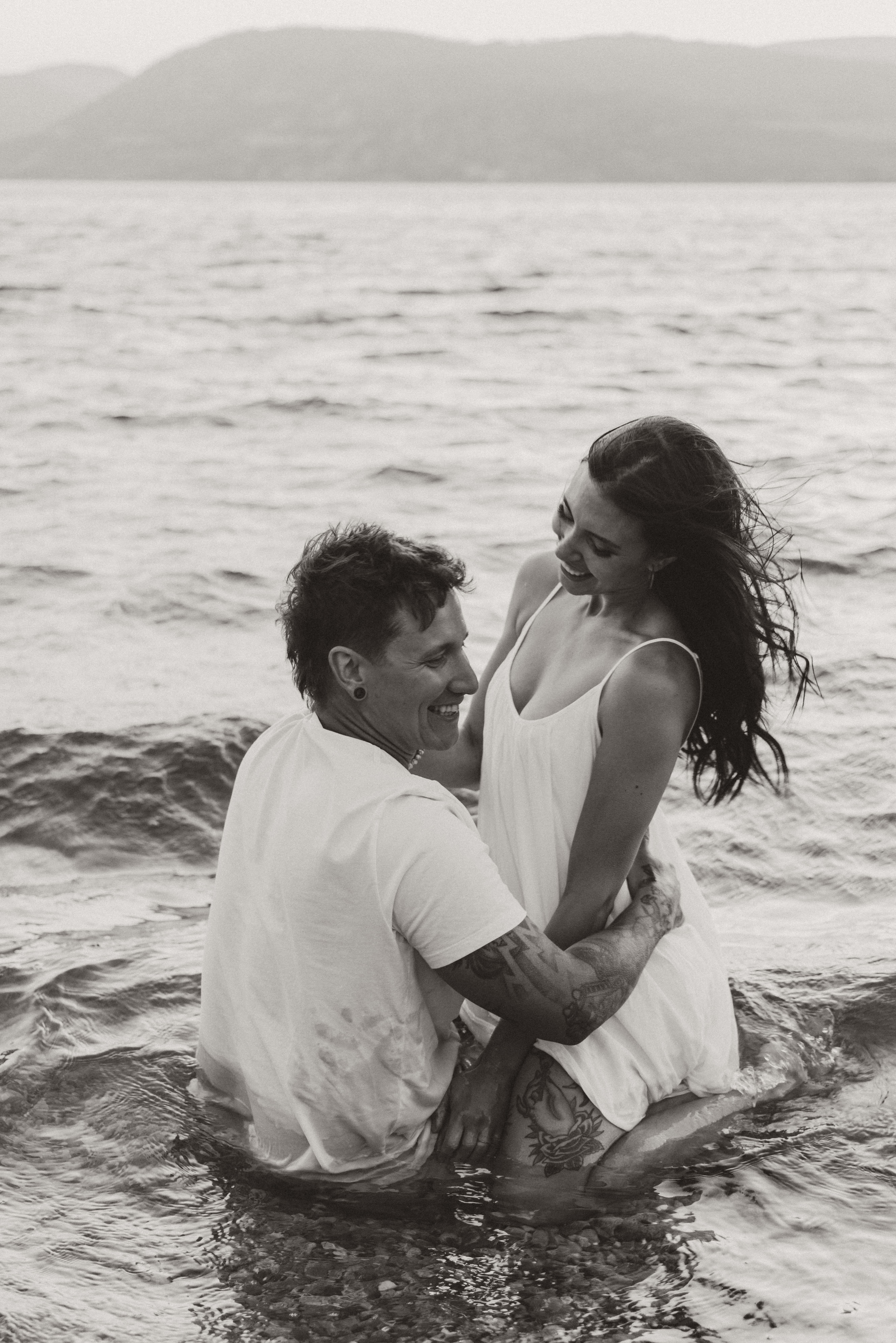 A gorgeous couple takes a dip in Lake Okanagan during their summertime golden hour engagement photoshoot