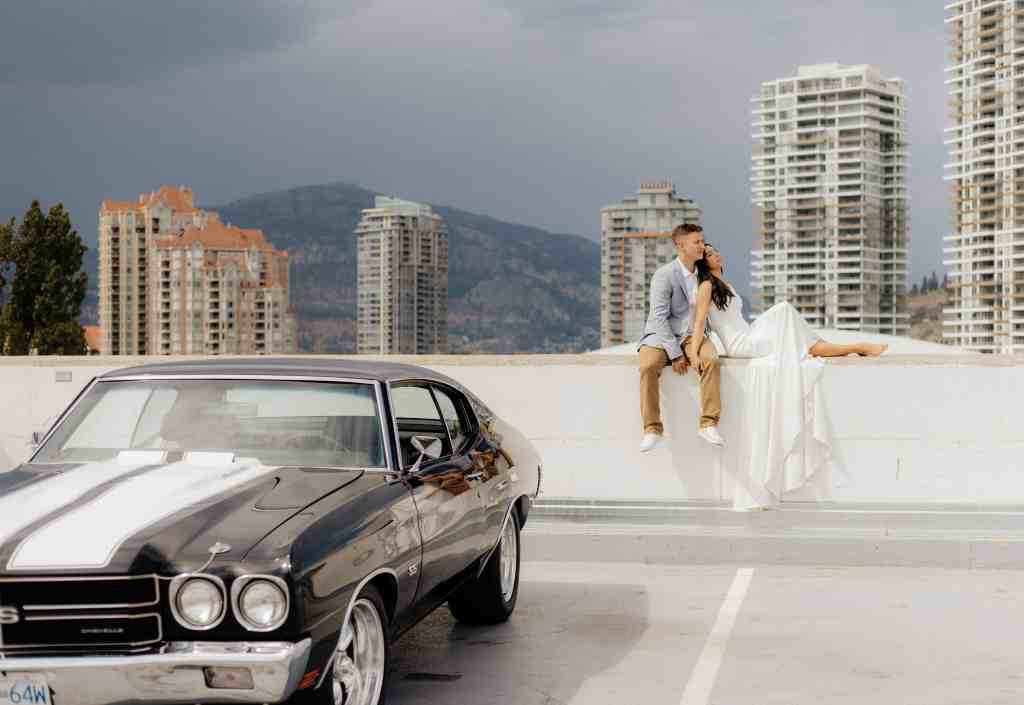 A couple poses with their gorgeous classic car on a parkade rooftop in downtown Kelowna