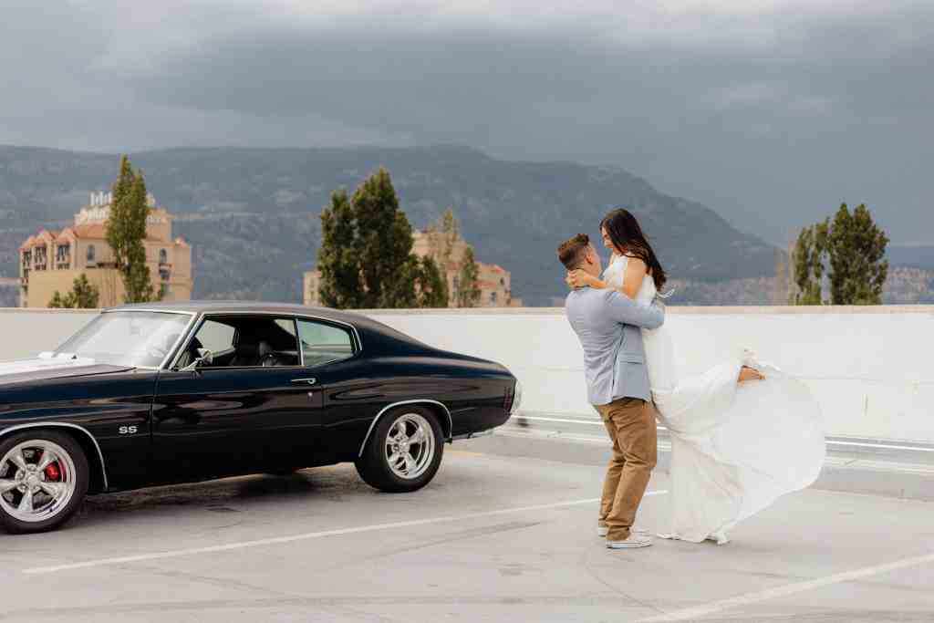 A happy bride and groom spin around on a rooftop during their wedding portrait session in downtown Kelowna, BC