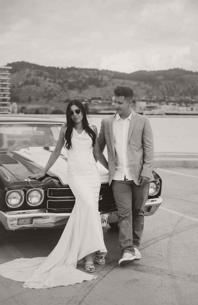 An editorial photo of a cool bride and groom standing by their classic car downtown during their wedding portraits in Kelowna, BC