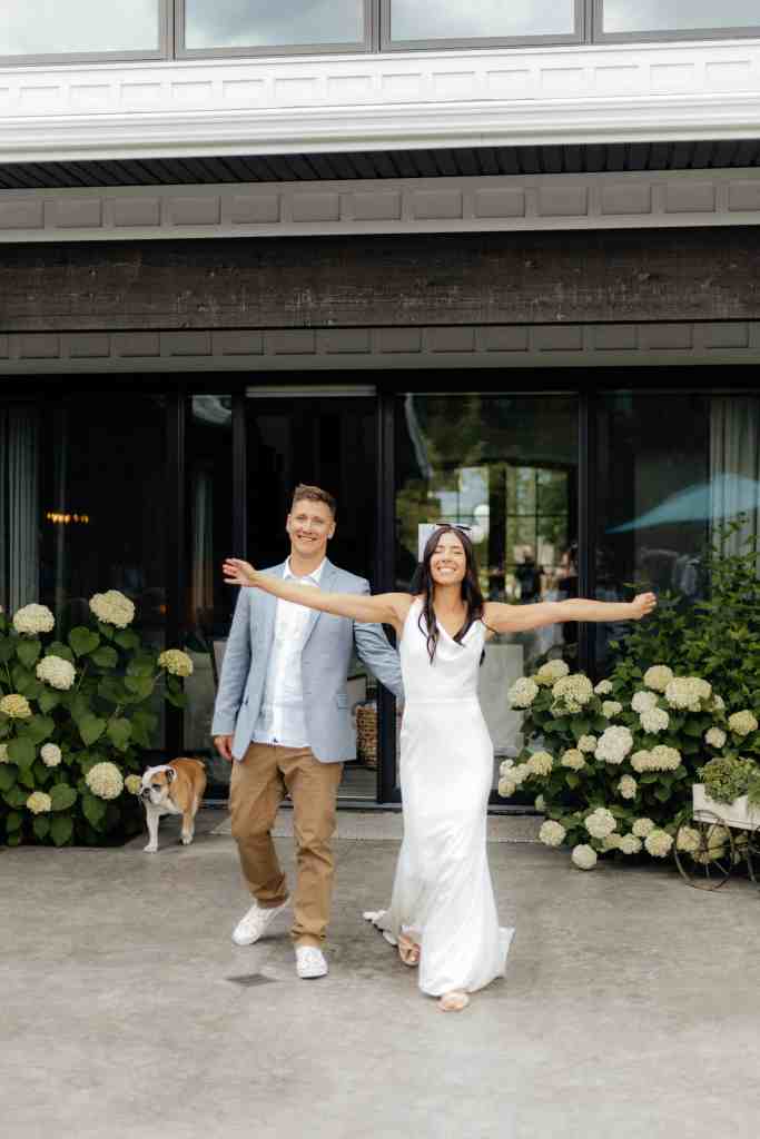 A bride and groom happily enter their backyard wedding reception with their dog in Kelowna