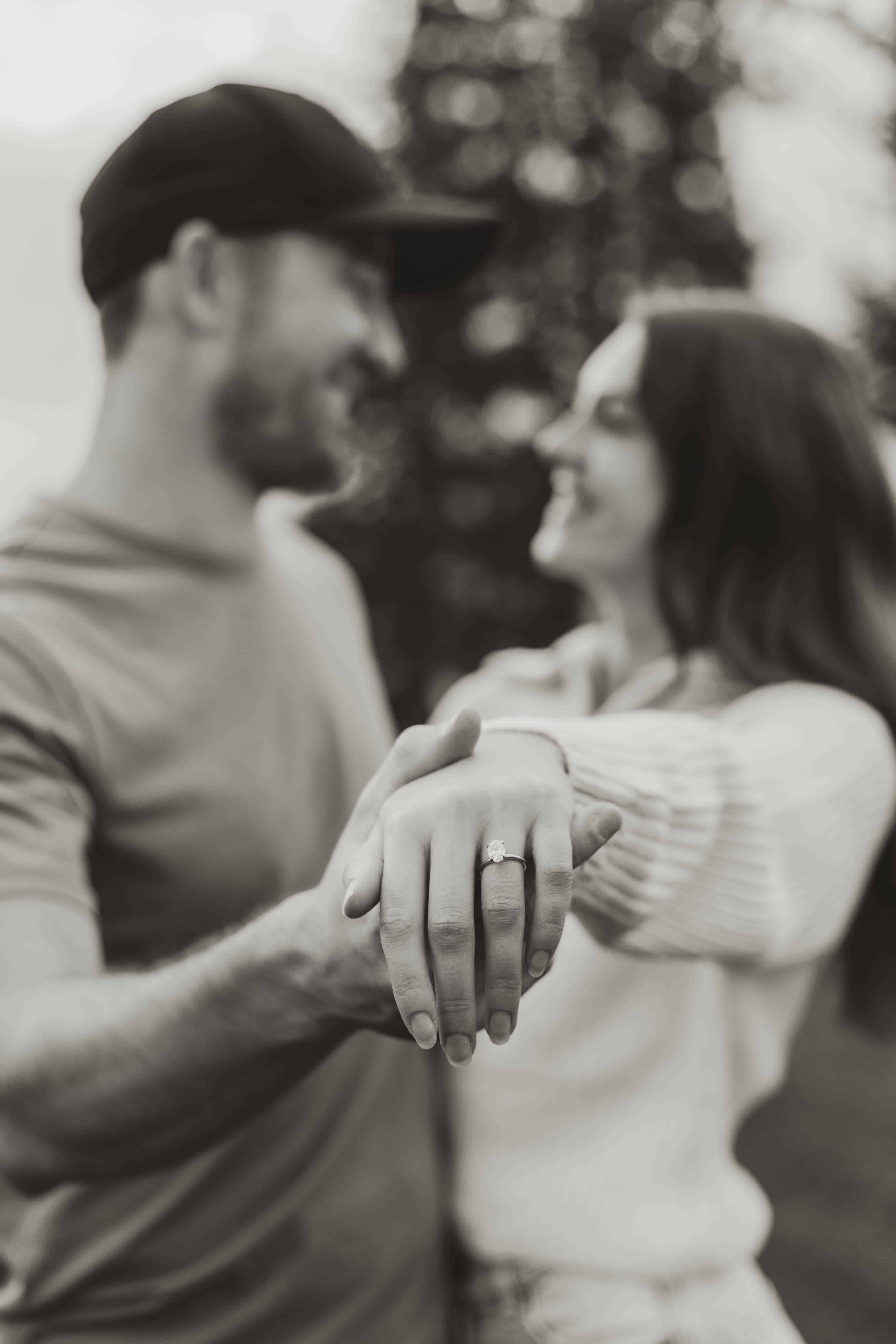 A black and white photo of a couple showing off an engagement ring at Bertram Creek Park, Kelowna