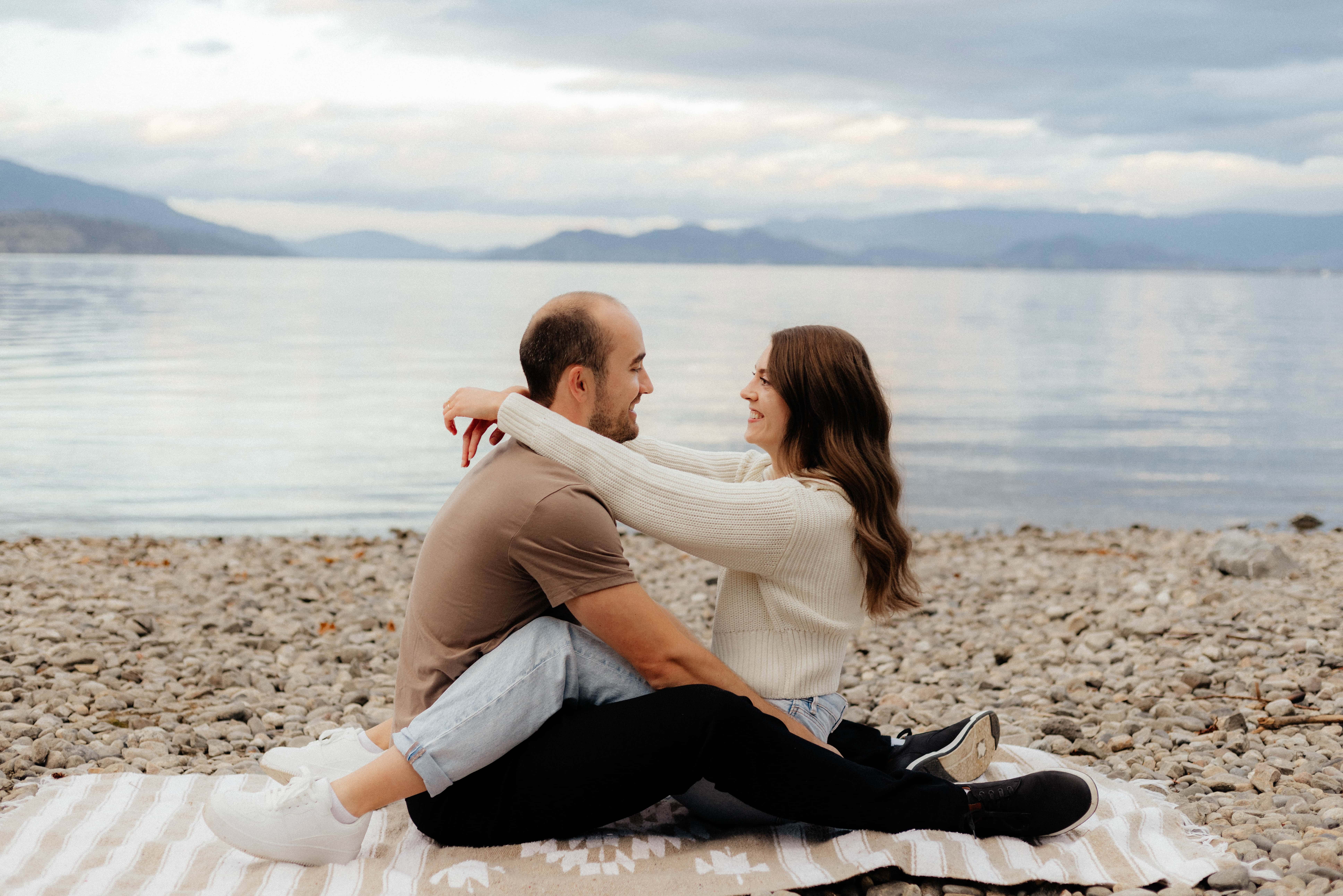 A couple snuggle up on the rocky beach of Lake Okanagan at Bertram Creek Park in Kelowna