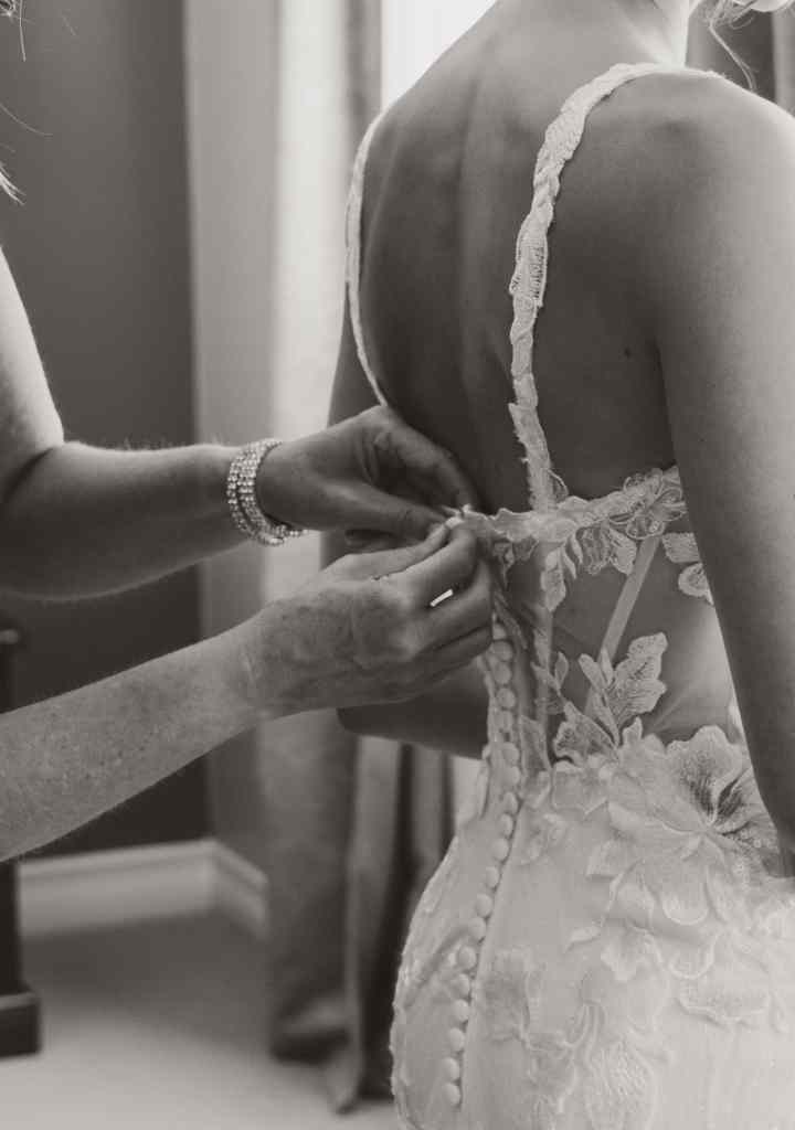 A mother does up the buttons on her daughter's wedding dress before the ceremony at Summerhill Winery, BC