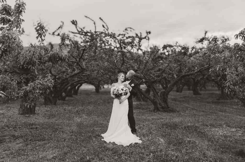 A bride and groom sharing a sweet candid moment together in an orchard in the Okanagan, British Columbia