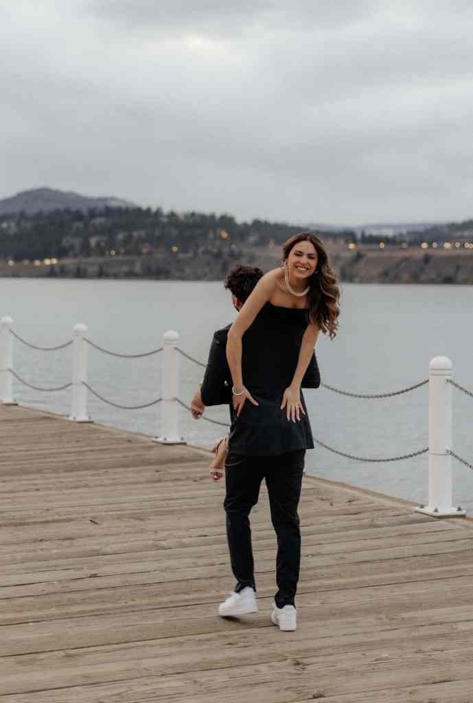 A man walks along the boardwalk of Lake Okanagan in Kelowna with his girlfriend over his shoulder as they laugh