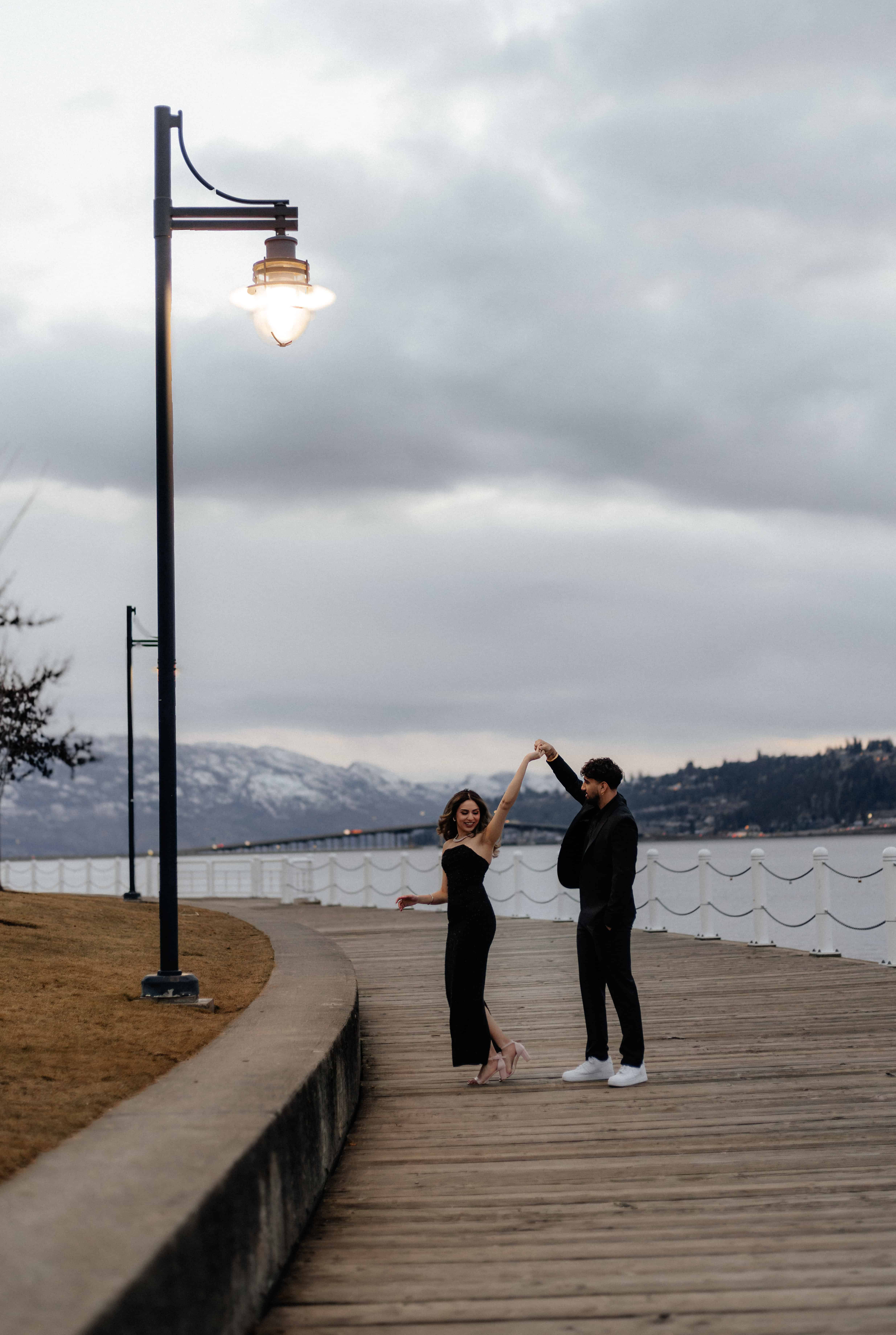 A photo of a couple dancing underneath the light of a streetlamp on the boardwalk in front of Lake Okanagan in downtown Kelowna
