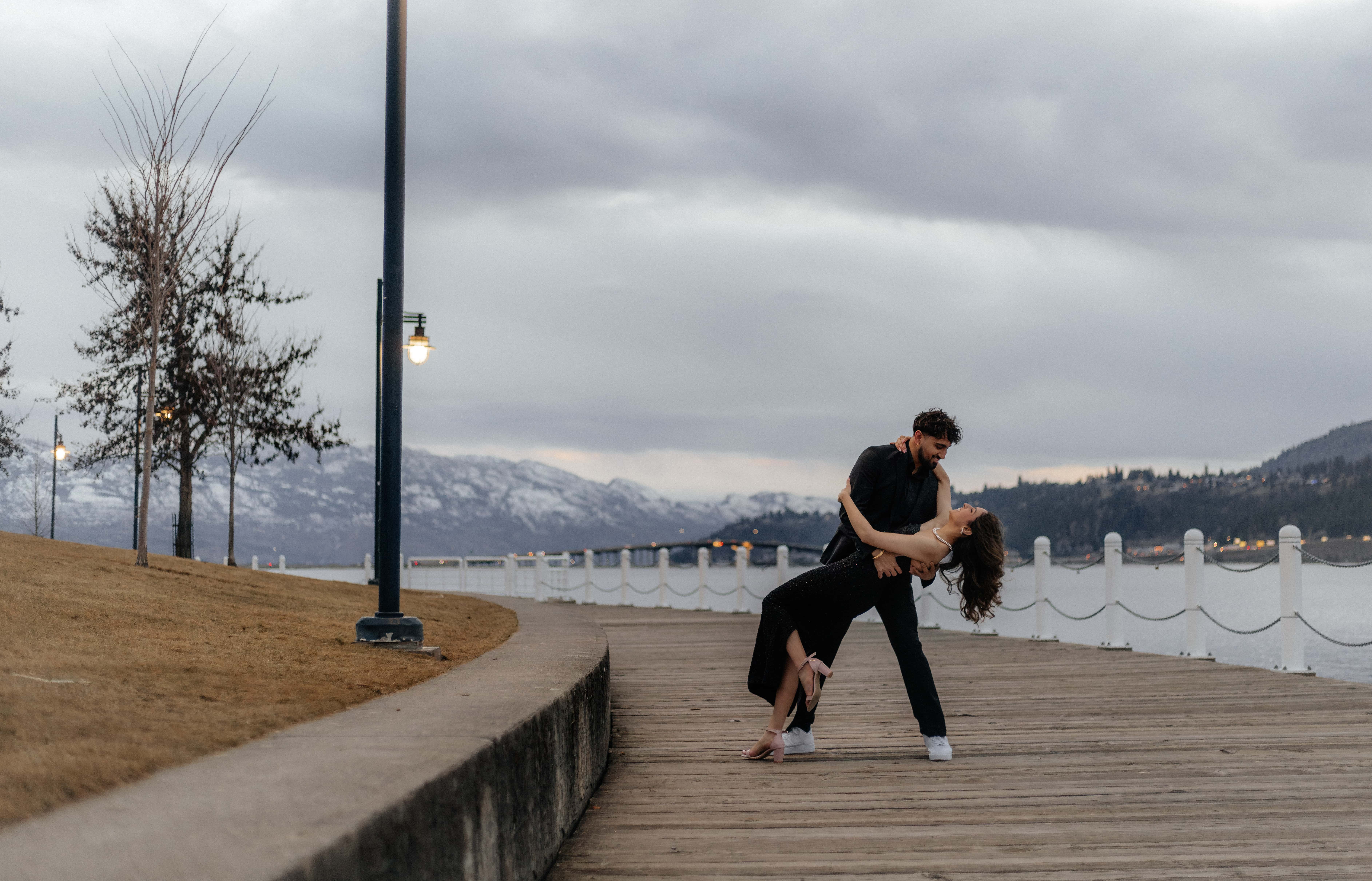 A glamorous couple does a dip in front of Lake Okanagan at twilight in downtown Kelowna, BC