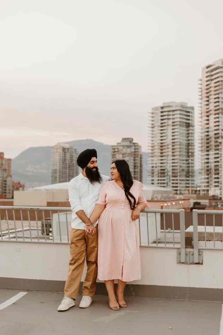 An Indian couple poses for a rooftop portrait in downtown Kelowna, wearing outfits they chose using this outfit guide