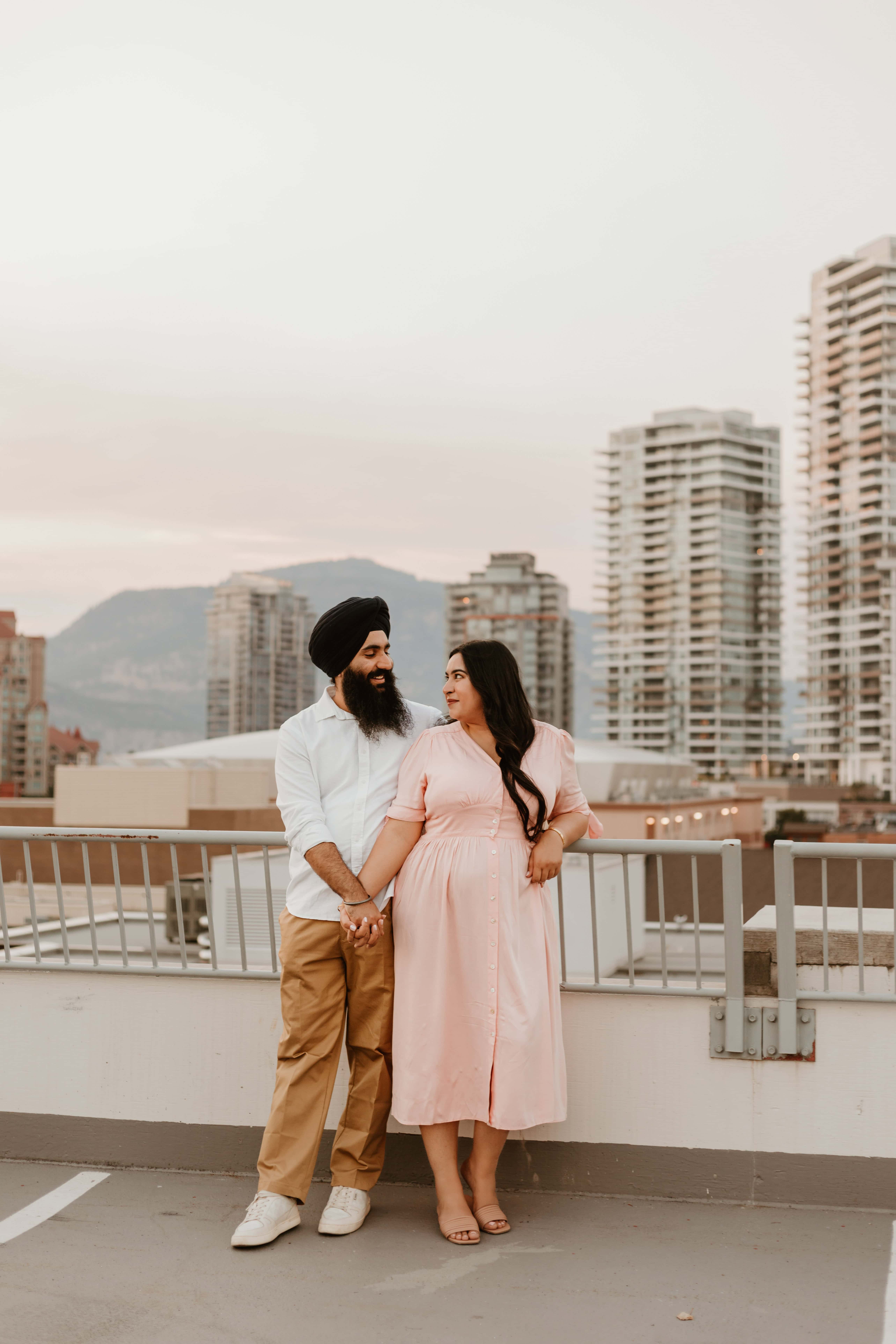 An Indian couple poses for a rooftop portrait in downtown Kelowna, wearing outfits they chose using this outfit guide