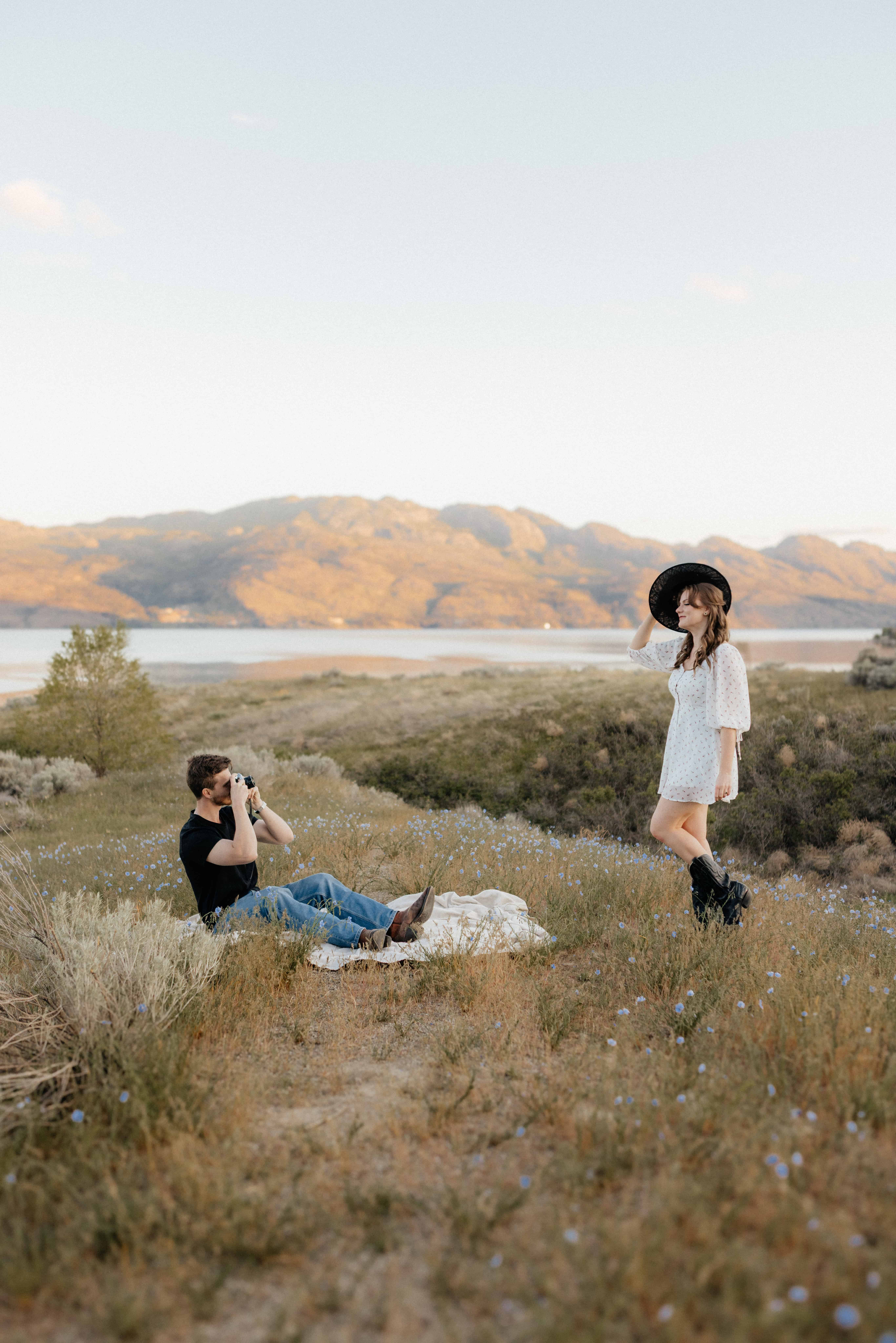 A man takes a candid photo of his fiancée during an engagement session at Sanctuary Gardens, West Kelowna