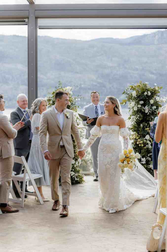 A couple walks up the aisle after tying the knot at their wedding ceremony at Grey Monk Winery in Lake Country, BC