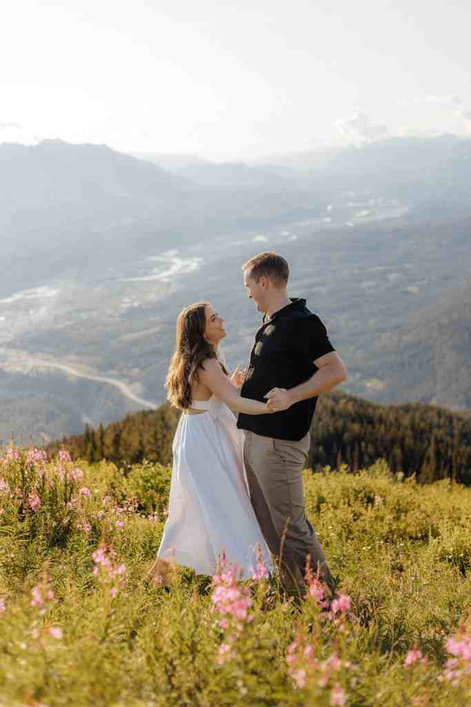 A couple dances on a mountain top during their engagement session in Golden, British Columbia