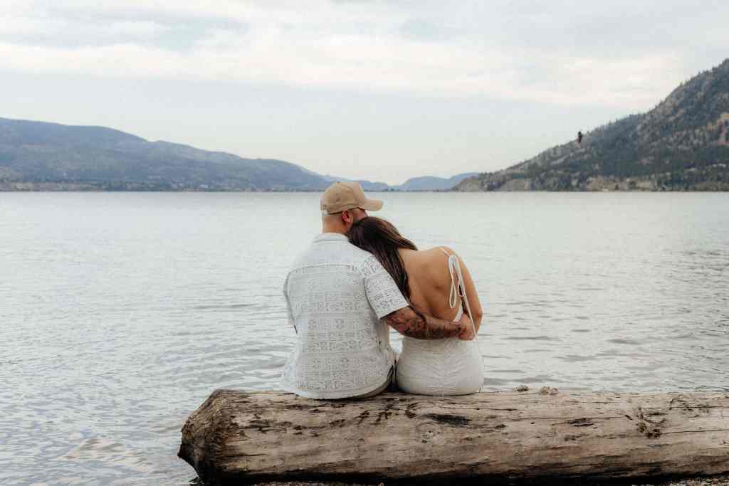 A couple snuggles on the beach during their engagement session at Sun-Oka in Summerland BC