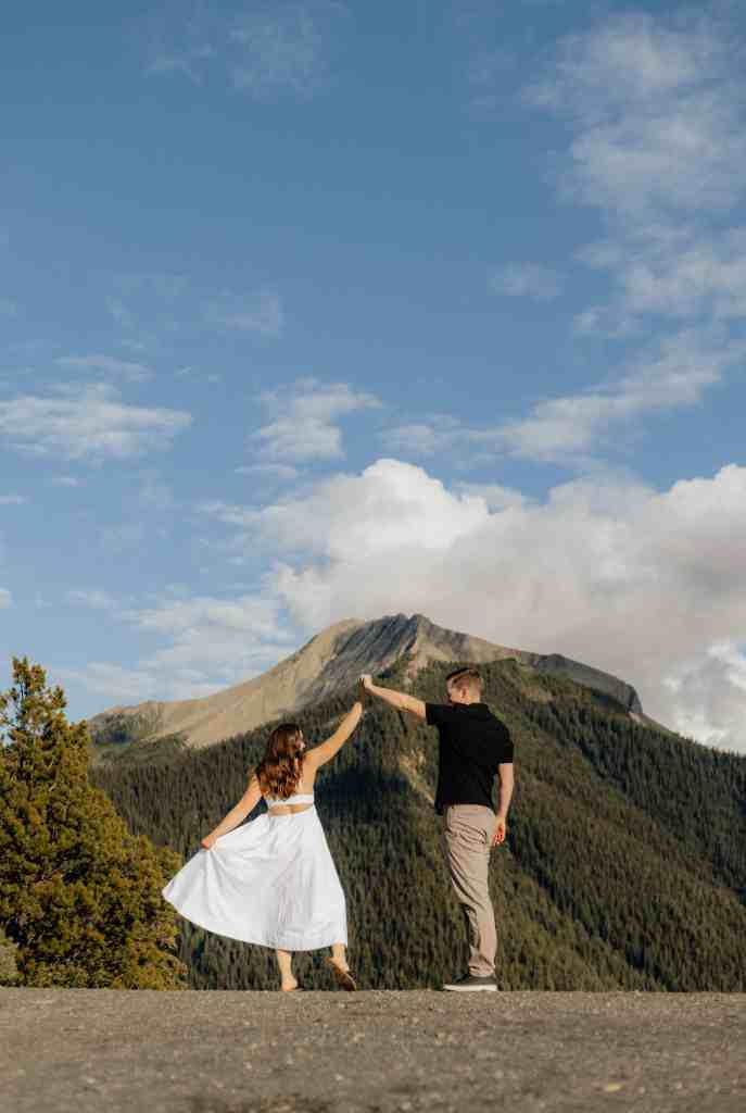 A couple dances on a mountaintop during their engagement session in Golden, BC