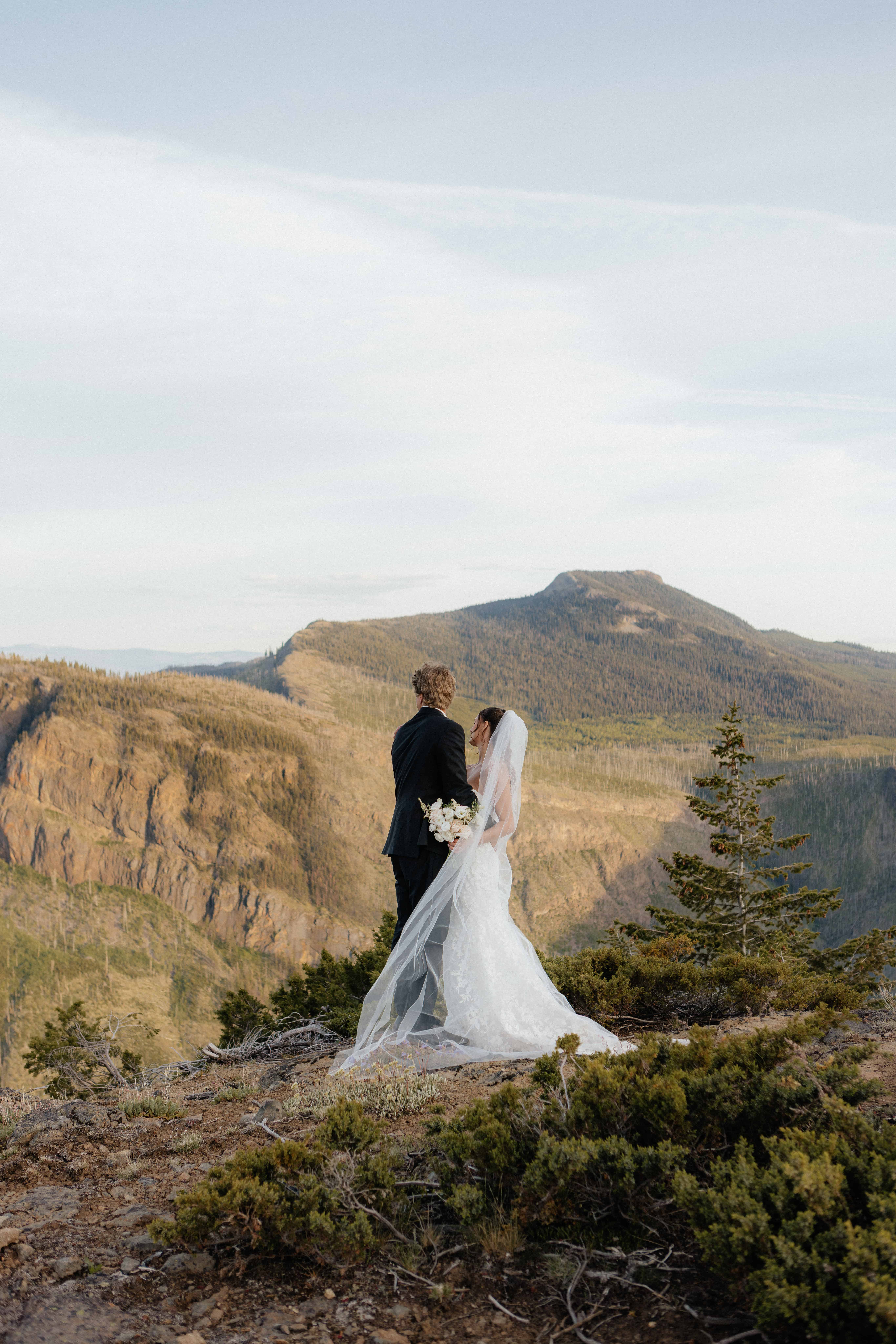 A bride and groom look out at the beautiful Okanagan mountains after their heli-elopement near Kelowna, BC