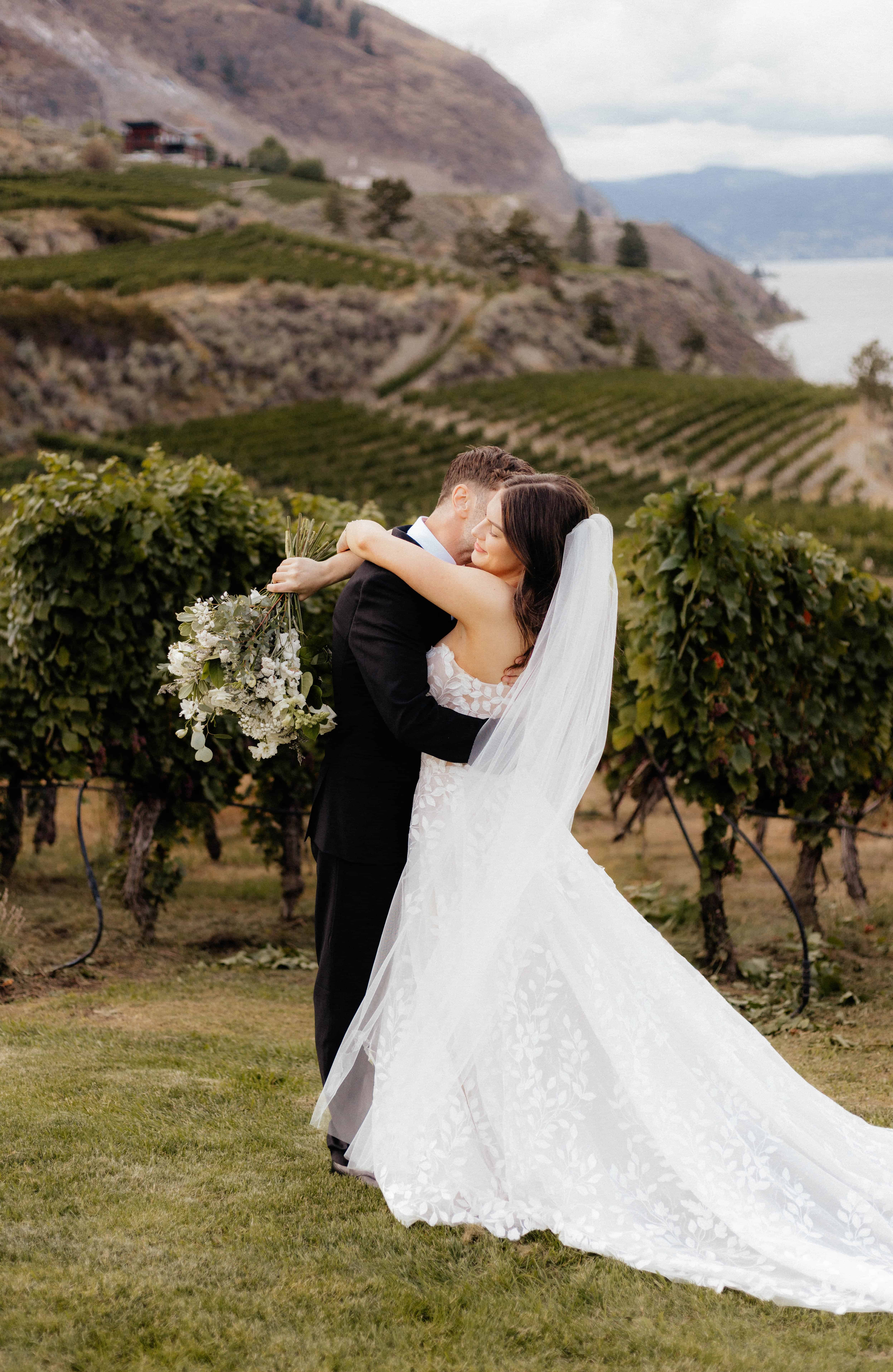 A groom kisses his bride on the cheek at Vows and Vines vineyard in Summerland, BC
